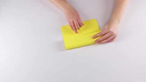 Hands Folding Yellow Paper to Create Pattern