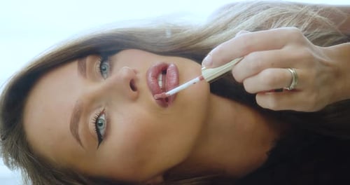 Closeup View of a Woman Paint Lips in Front of a Mirror
