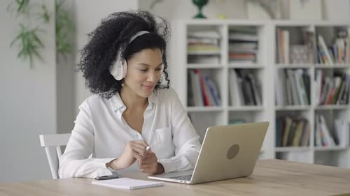 Woman Working on Laptop Computer with Headphones at Home