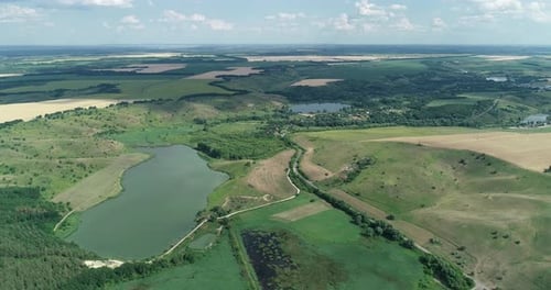 Drohnenschuss über wunderschöne grüne Wiesen, Hügel und See