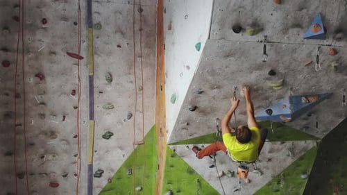 Young Man Rock Climber is Climbing At Inside Climbing Gym
