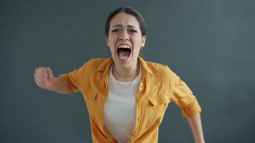 Portrait of Young Lady Screaming and Gesturing Looking at Camera Fighting Expressing Rage