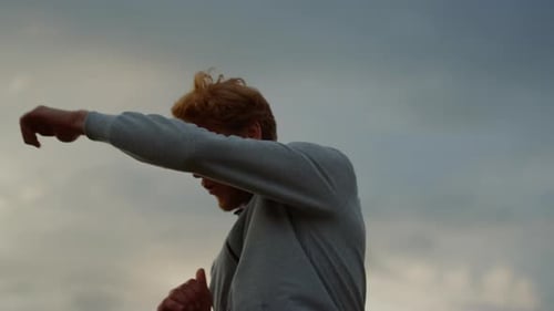 Man Shadow Boxing Outdoors on Cloudy Day