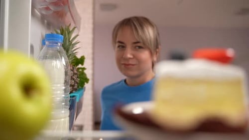 Woman Chooses Apple over Cake from Refrigerator
