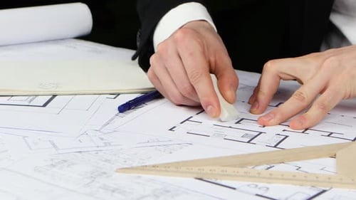 Builder Sits at the Table and Analyzes the Drawing of the New Store. Close Up
