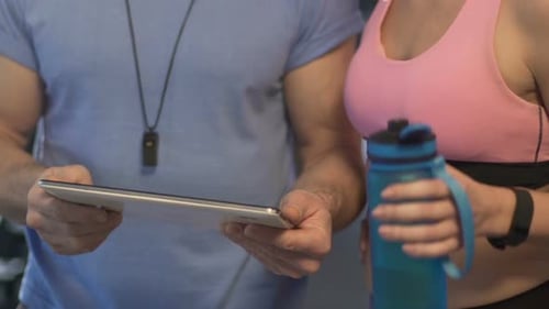 Trainer and Woman Reviewing Fitness Plan on Tablet