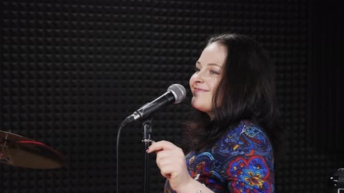 Joyful happy woman is singing to microphone, dancing and having fun