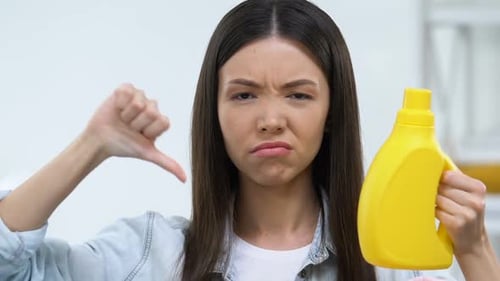 Dissatisfied Woman Holding Washing Gel and Showing Thumbs-Down Sign, Dislike