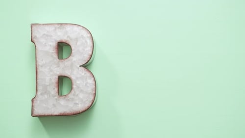 Woman Arranges Letters Spelling BBQ on Green Surface