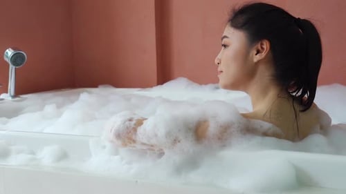 Woman Relaxing in a Bubble Bath in Bathroom