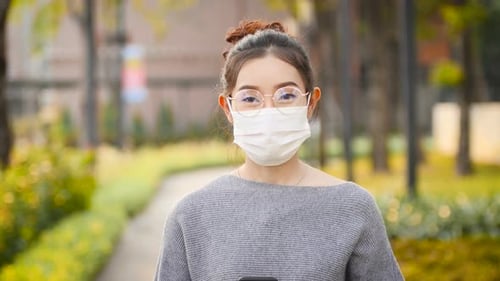 Woman Wearing Mask Using Phone in Sunny Park