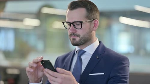 Focused Businessman Using Mobile Smartphone at Workplace