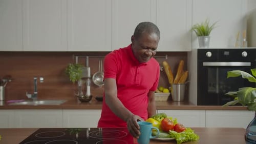 Man Clutching Chest in Pain in Kitchen