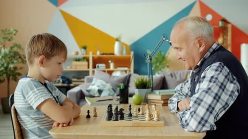 Porträt von Großvater und Enkel beim Schachspielen und Schachmänner an Bord bewegen
