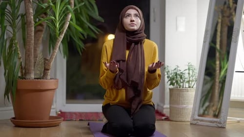 Religiöse muslimische Frau betet abends zu Hause sitzend