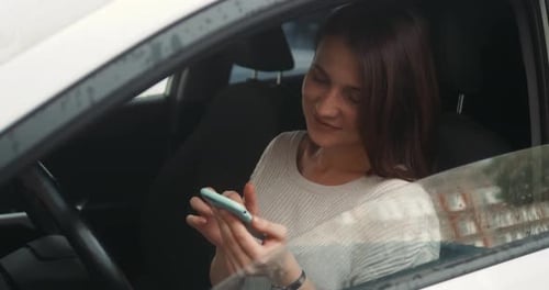 Glückliche Frau sitzt im Auto mit einer Smartphone-Spracherkennungsfunktion, Online-Sprache im Freien