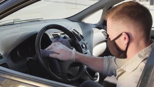 Man Cleans Car Steering Wheel Wearing Mask