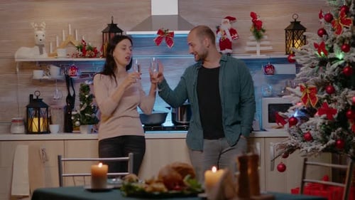 Couple Celebrating Christmas with Champagne in Kitchen