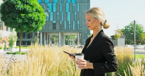 Pensive Businesswoman Walking Around Urban Setting in Financial District with Coffee to Go and Cell