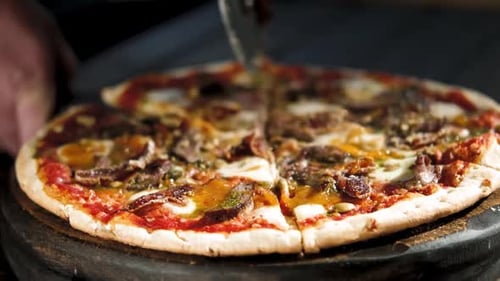 Closeup Hand of Chef Baker Cutting Pizza at Kitchen