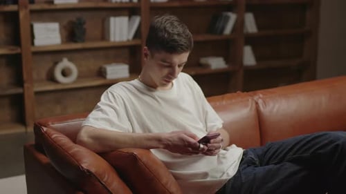Man Relaxes on Couch Using Smart Phone