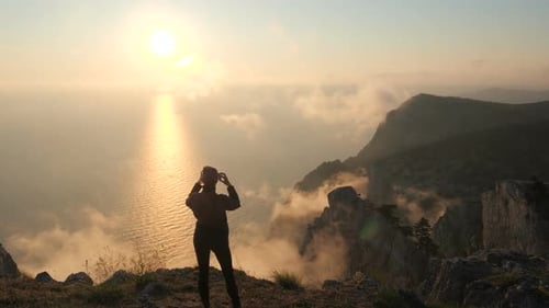 The View From the Back of a Sporty Young Woman Who Takes Photos of a Beautiful Sunset Over the Black