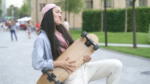 Young Woman Playing Skateboard Like Guitar in City