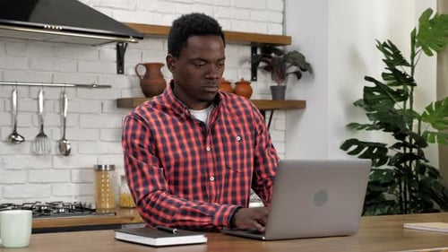 Young Adult Working on Laptop in Kitchen