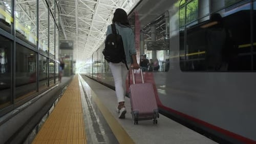 Young Woman Pulling Suitcase on Train Platform