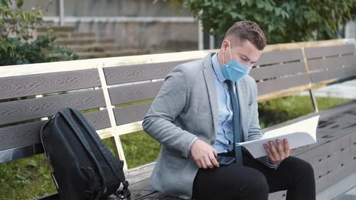 Man Reviewing Documents While Sitting on Bench