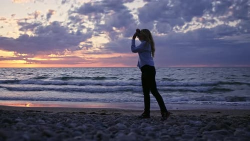 Photographer Using Camera On Beach At Sunset
