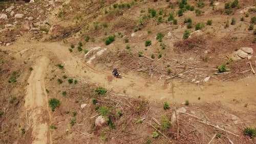 Aerial View of Motorcyclist Ride on Dirt Road in the Mountains Down Hill.