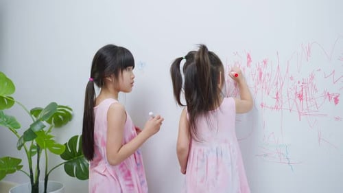 Asian young sibling kid girl enjoy paint on white wall in living room.