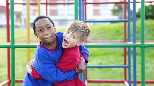 Young interracial friends laugh and give big hugs to each other at the park