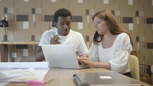 Two Adults Work Together on a Laptop