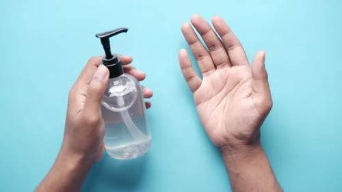 Top View of Man Using Sanitizer Liquid on Blue Background
