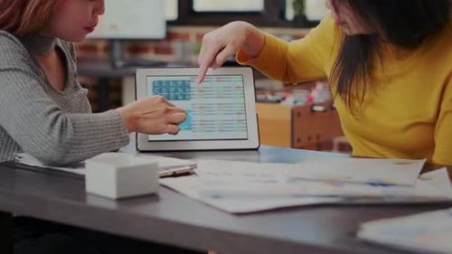 Des collègues examinent les statistiques boursières sur tablette