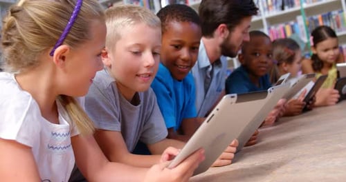 School kids and teacher using digital tablet in library