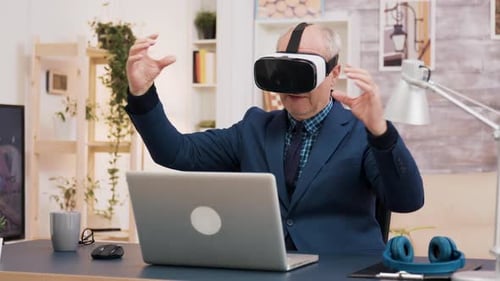 Senior Man Uses VR Headset at His Desk