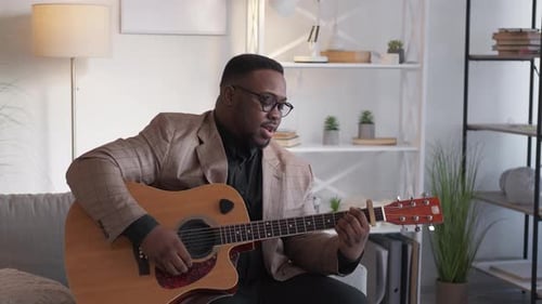 Man Plays Guitar and Sings in Living Room