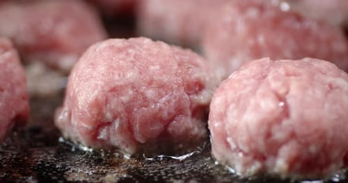 Rohe Fleischbällchen in einer Pfanne mit Luftblasen braten.