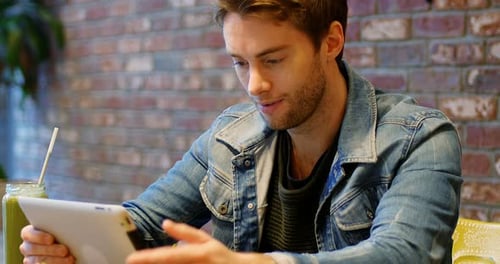 Man using digital tablet with glass of juice on table