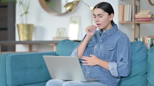 Young Adult Coughing While Working on Laptop