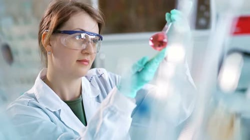 Woman Scientist Examining Pink Liquid in Flask