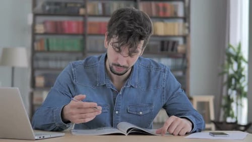 Young Man Reading Magazine Book in Casual Office