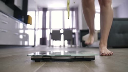 Woman Steps on Bathroom Scale with Measuring Tape