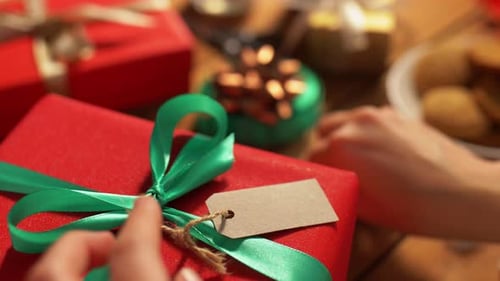 Hands Attaching Name Tag To Christmas Gift