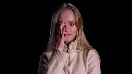 Vista aproximada de uma mulher loira de suéter branco, mantenha segredo e olhe para a câmera em preto