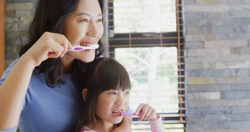 Mother and Child Brushing Teeth in Bathroom