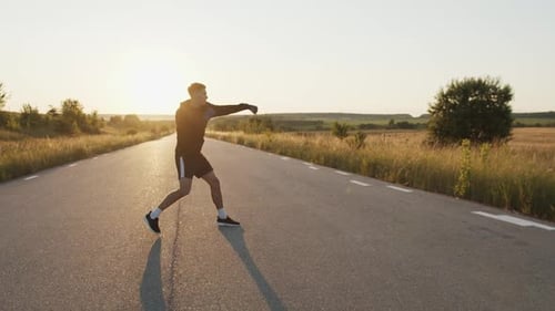 Man Training Boxing Drills on Rural Road at Sunrise